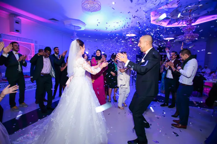 Mariés qui dansent sous une pluie de confettis en salle de réception